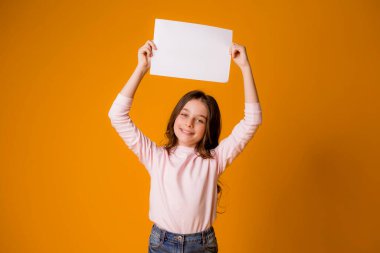 Stüdyoda turuncu arka planda sevimli küçük bir kız.