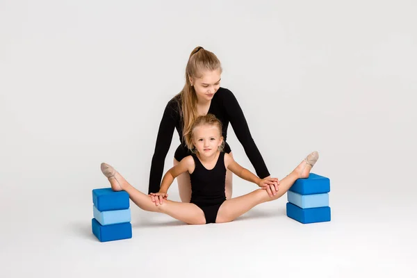 Genç kız jimnastik koçu ve beyaz arka planda küçük kız öğrencisi.