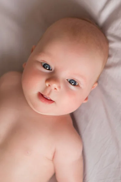 快乐的3个月大的宝宝笑着躺在白色的床上 — 图库照片