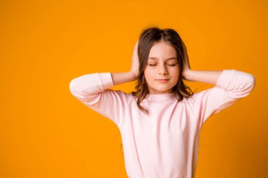 Stüdyoda turuncu arka planda sevimli küçük bir kız.