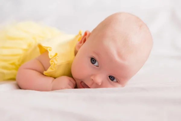 Dziewczynka Miesiące Żółtej Sukience Trzyma Stokrotkę Leży Łóżku Domu — Zdjęcie stockowe