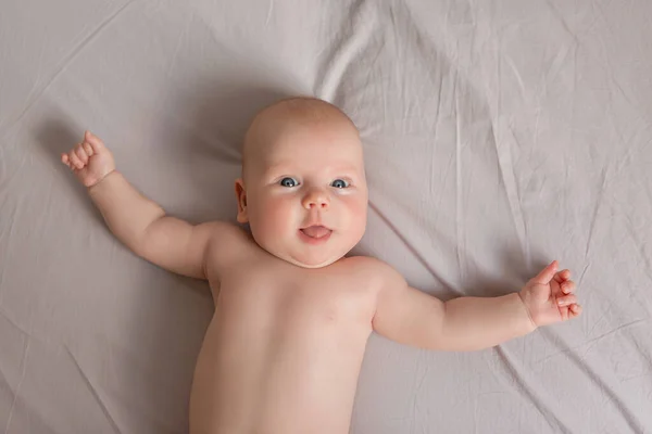 快乐的3个月大的宝宝笑着躺在白色的床上 — 图库照片