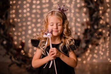 Siyah elbiseli küçük kız poz veriyor.