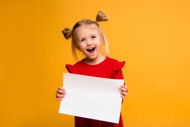 Sarı arka planda beyaz bir çarşaf tutan bir kızın fotoğrafı. Reklam metniniz için boşluk resmini yerleştirerek kopyalayın