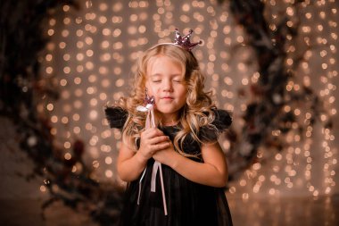 Siyah elbiseli küçük kız poz veriyor.