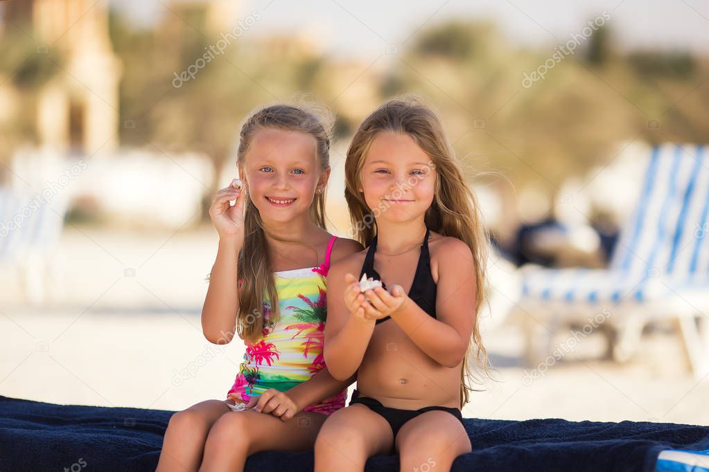 Two beautiful happy girls on the beach by the sea on vacation
