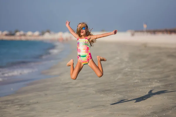 Mutlu çocuk yaz tatil egzotik tropik sahilde atlama. Küçük çocuklu aile için okyanus kıyısında tatil. Çocuklar oyun denizde.