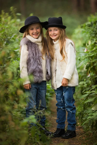 つの幸せな女の子は同じように服を着ている 毛皮のベストと帽子フォレスト内の 公園の小さなガール フレンド 幸福概念を笑って一緒に子供たちの友情 — ストック写真
