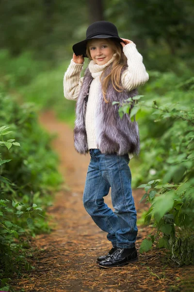 春の女の子の肖像画 黒の帽子と毛皮のベストの大きな茶色の瞳と甘い女の子 バック グラウンド ツリーで — ストック写真
