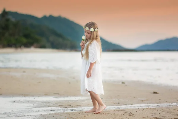 夕暮れ時のビーチで花と甘い女の子 — ストック写真