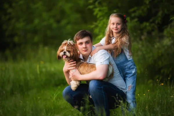 The concept of a happy family. Older brother and a younger sister with a dog on the lawn