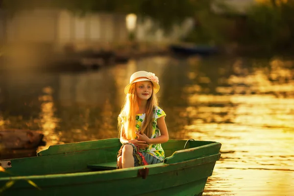 サンセット ボートで湖に座っている帽子でかわいい女の子 — ストック写真