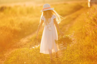 Mutlu genç çekici kız bir alanda gün batımında yürüyüş