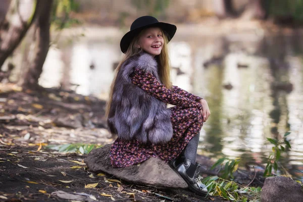 Güneşli de akşam nehir kenarında oturan uzun saçlı güzellik çocuk kız