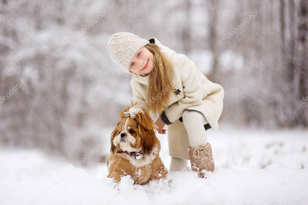 In winter, snow falls in the snowy forest,  little girl play with dog.
