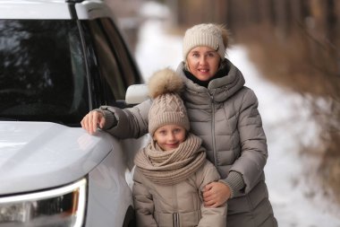 Anne ve kızı yanında beyaz bir araba