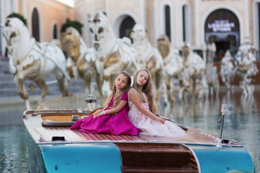 Yemyeşil moda elbiseler iki güzel kızın bir teknede tatilde otur. Poz kızlar.