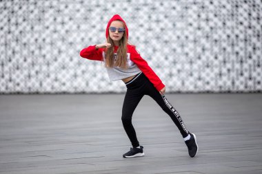 Eşofmanlı küçük kız sokakta modern dans ediyor. Genç şehirli hip hop dansçısı