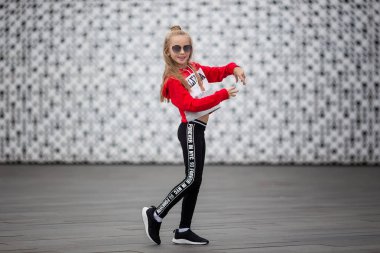 Eşofmanlı küçük kız sokakta modern dans ediyor. Genç şehirli hip hop dansçısı
