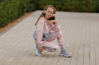 Mutlu sarışın kız kulaklıkla müzik dinliyor, sokakta dans ediyor..