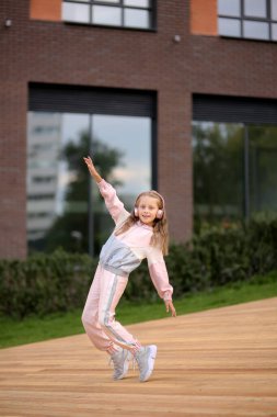 Eşofmanlı küçük kız sokakta modern dans ediyor. Genç şehirli hip hop dansçısı