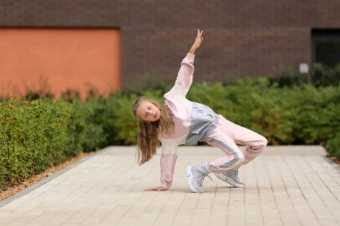 Eşofmanlı küçük kız sokakta modern dans ediyor. Genç şehirli hip hop dansçısı