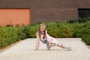 Eşofmanlı küçük kız sokakta modern dans ediyor. Genç şehirli hip hop dansçısı