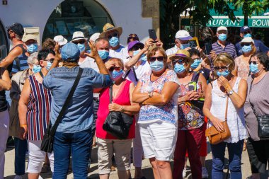 Saintes Maries de la Mer - 09 / 04 / 2020: Saintes Maries de la Mer - 09 / 04 / 2020: bir rehberi dinleyen maske takan turistler