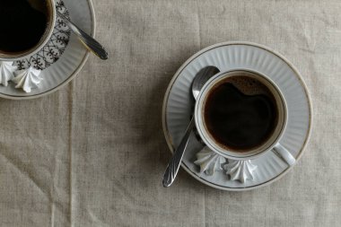Kahve demliği ve fincanlar açık arkaplanda açık keten bir masa örtüsüyle masanın üzerinde kahve.
