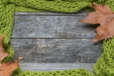 Eski ahşap bir masanın üzerinde yapraklarla örülmüş bir şal.