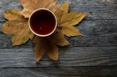 Eski ahşap bir masada bir fincan çay.