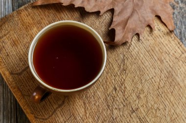 Eski ahşap bir masada bir fincan çay.