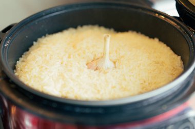 Siyah bir tencerede sarımsak kafalı pilav pişirdim. Sıcacık ve ağız sulandırıcı bir yakın çekim ev yapımı yemeğin basit güzelliğini yakalıyor.