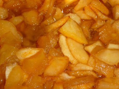 Tatlı şurupta kaynayan kehribar renkli elma parçalarının yakın çekimi..