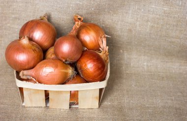 Hasır sepette altın soğan yuvarlağı, doğal ev yapımı arka planda ahşap bir kutu yarım düzine peçete, faydalı sebze vitaminleri, metin için kopyalama alanı.