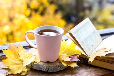 Sonbahar yaprakları, eski kitaplar ve tahta bir yüzeyde bir fincan çay. Güzel bir arka plan. Açık hava kampı. Sonbahar yaşam tarzı, konfor kavramı