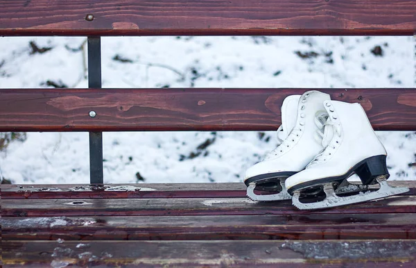 white figure skates lie on a wooden bench, active winter recreation, healthy lifestyle