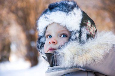 Kışın sıcak giysiler içinde bir çocuğun portresi bir kış parkının arka planında yakın plan, arka plan güzel bulanıklık, metin için boşluk