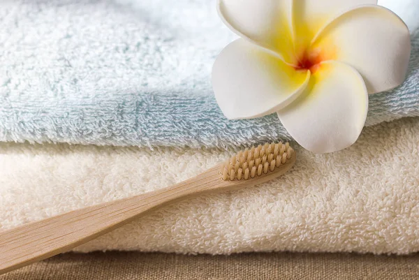 Wooden eco-friendly toothbrush terry towel and decorative flower on textile natural canvas background