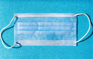 Parlak mavi arka planda tek kullanımlık tıbbi maske, grip koronavirüsü alerjisi ve hijyen teması, kişisel izolasyon