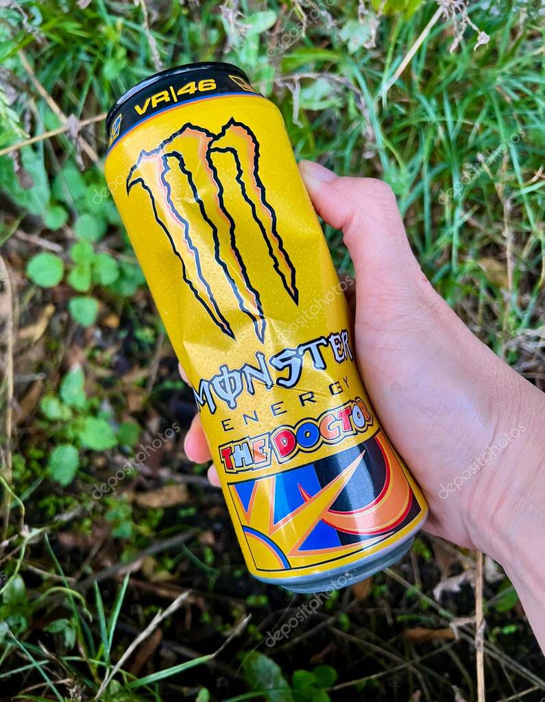 A crumpled aluminum can of the Monster energy drink in hand.