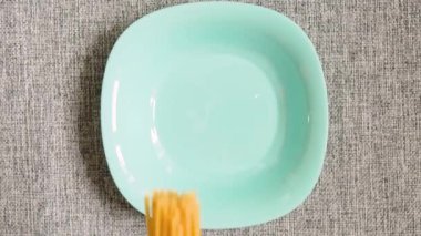 Spagetti turkuaz bir tabağa düştü ve dağılıyor. Ağır çekim, Üst Görünüm