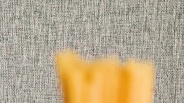 Spagetti gri arkaplana düştü ve parçalanıyor. Ağır çekim, Üst Görünüm