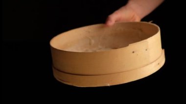 Kız ellerinin arasında elek tutuyor ve unu eleştiriyor.