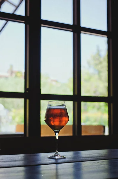 A glass of wine stands in front of a large window