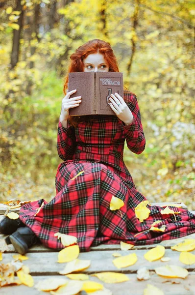 秋の公園で本を読んでいる若い女の子 — ストック写真