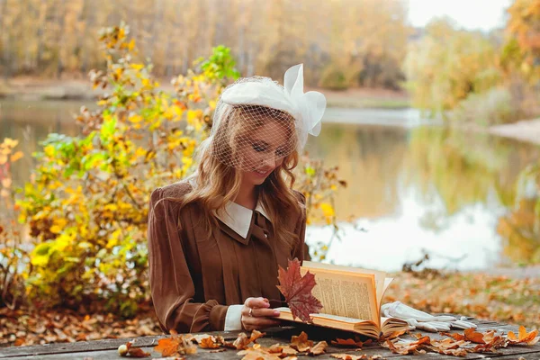 秋の公園で本を読むレトロなドレスの若い女性の肖像 — ストック写真