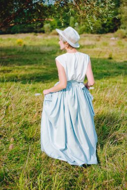 Doğada yürüyen mavi elbiseli zarif, mutlu bir bayan.