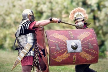 Gessate, Milan, Italy: April 07, 2019: reenactment of ancient Roman legionary soldiers during battle against Gallic army and life scene in war training camp with several dueling clipart