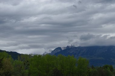 Blick auf die schweizer Berge im Fruehling bei bei woelktem Himmel